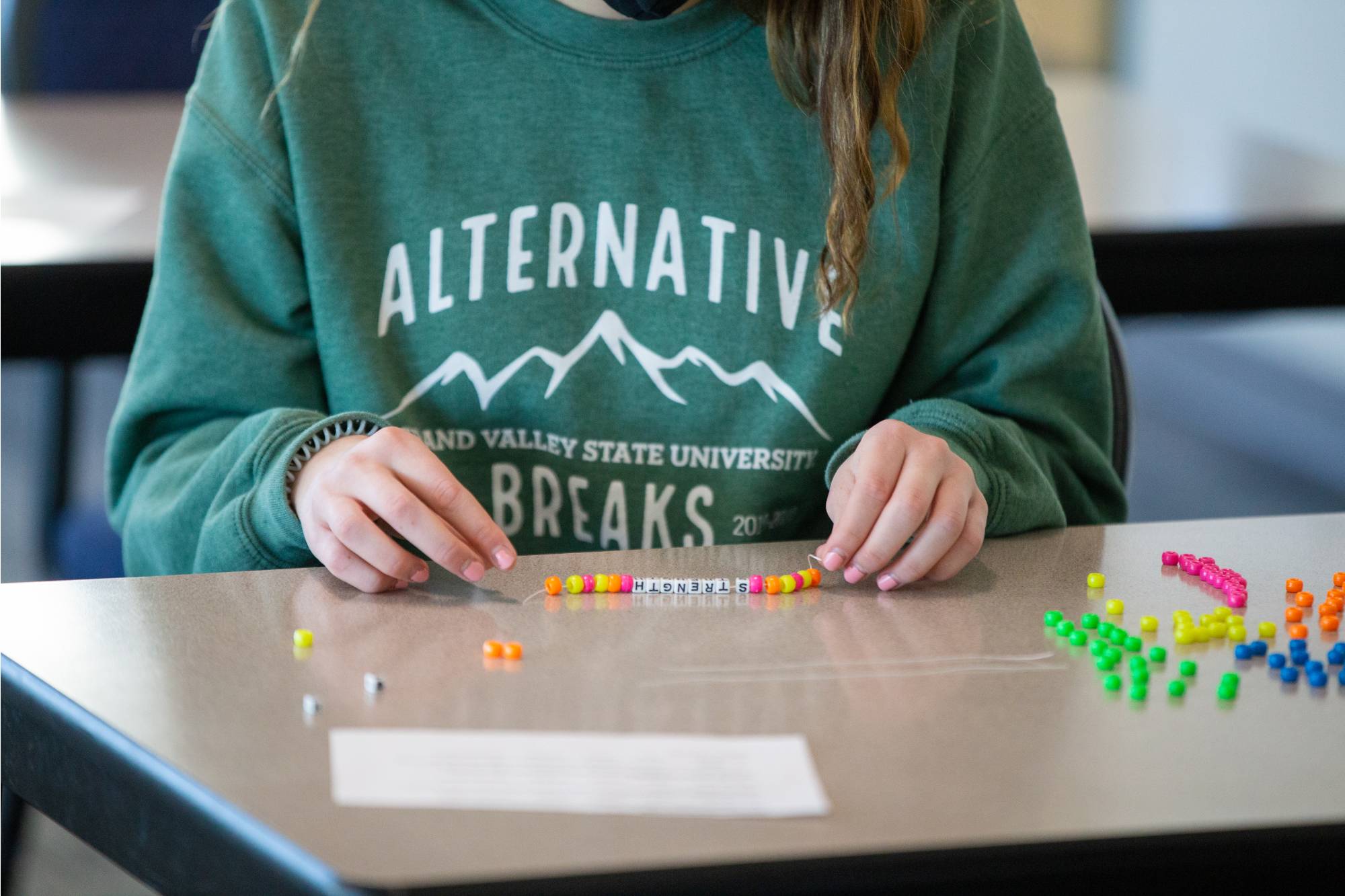 Student making a bracelet by putting beads onto a string